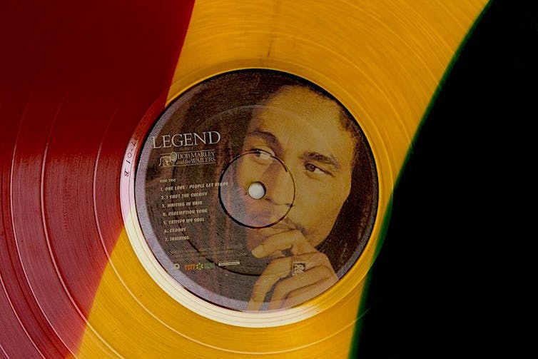 Un disco rojo, amarillo y verde con el rostro de un hombre pensativo con rastas.